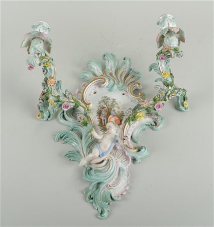 A porcelain wall amplique decorated with putti and flowers and in the middle...