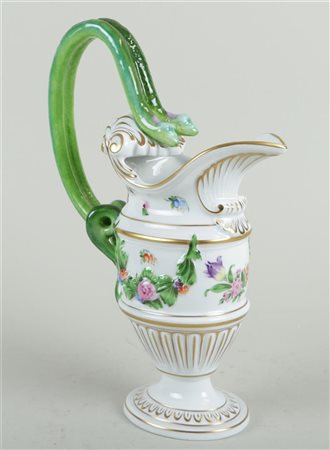 A porcelain jug with floral decoration and a handle in the shape of two...