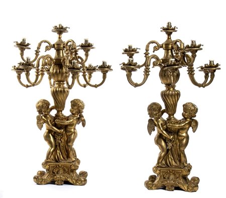 Coppia di candelieri a 9 luci in bronzo dorato e finemente cesellato con putti stanti a trattenere il fusto   