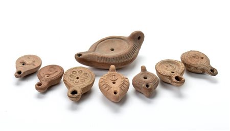 Lotto di 8 lucerne in terracotta con decori a rilievo rappresentanti guerriero, due lucertole con le code intrecciate, un'ariete, una colomba, un'ancora   