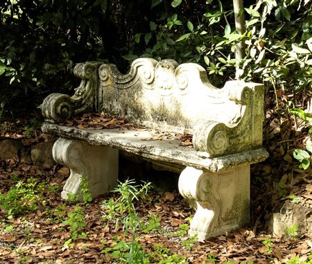 Panchina da giardino in polvere di cemento e marmo con schienale sagomato, braccioli e piedi a grandi volute   