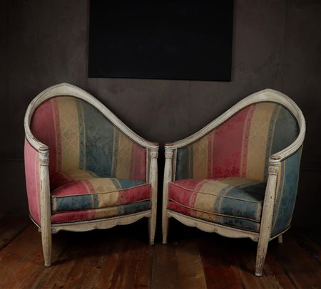 A pair of white lacquered French club chairs with striped upholstery.