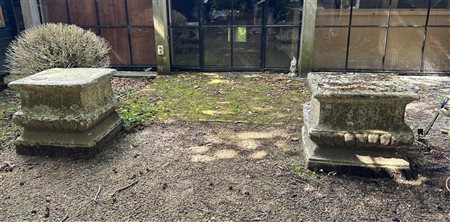 A set of two identical weathered stone garden plinths.