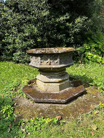 A hexagonal stone baptismal fountain on a pedestal. In the sides Gothic...