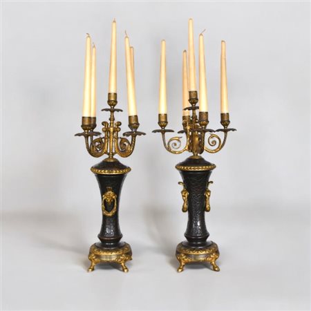 Coppia di candelabri in metallo dorato ed in parte brunito