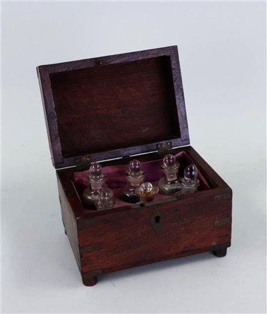 A wooden cabinet inlaid with brass. In it cold-painted glass perfume bottles...