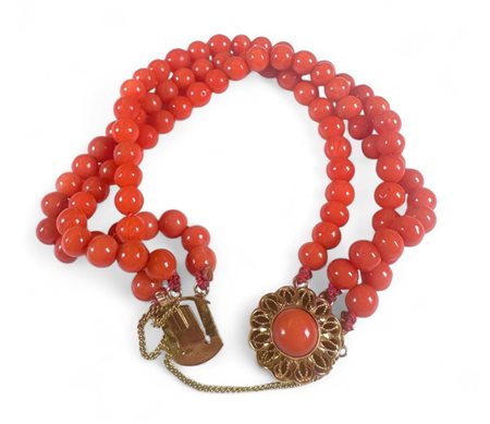 A blood coral bracelet with openwork twisted gold clasp, inlaid with a round...