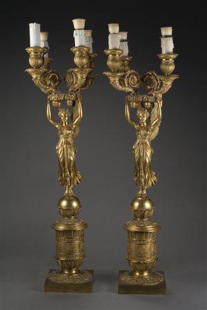 Coppia di candelieri in bronzo dorato a quattro fiamme decorati da figura a...
