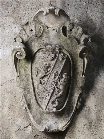 Stemma nobiliare in pietra di forma sagomata decorato a volute e leoni...