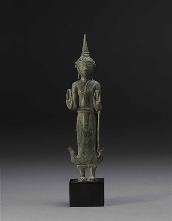 Buddha in bronzo raffigurato in piedi, il volto con espressione sorridente e...