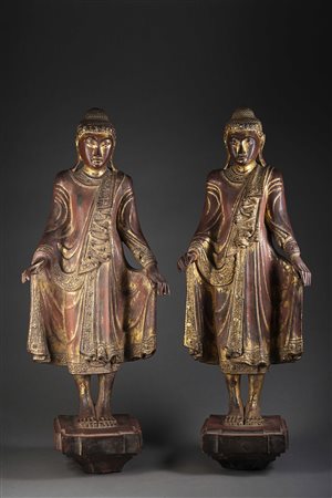 Coppia di Buddha in legno laccato e dorato, raffigurati stanti, su basi...