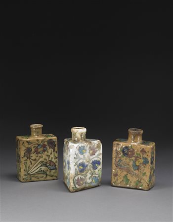 Tre bottiglie in terracotta decorata con smalti sottocoperta, due di forma...