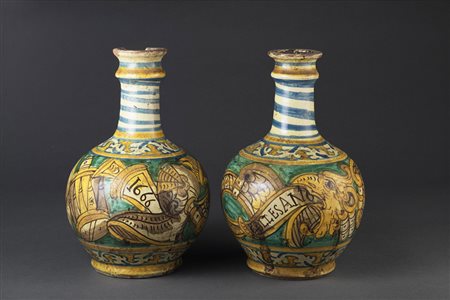 Coppia di bottiglie in maiolica policroma. La parte centrale si presenta di...