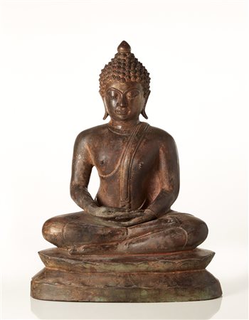 Buddha in bronzo raffigurato seduto, il volto con espressione serena, i...