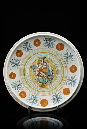 Alzata tonda con piccolo piede in maiolica policroma. Profilo liscio con...