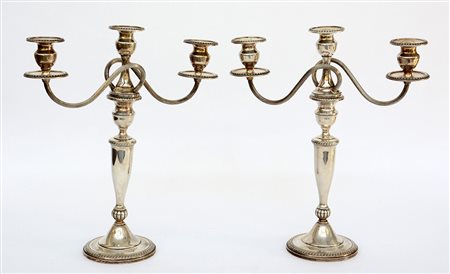 Coppia di candelabri a tre fiamme in argento. Fusto svasato decorati a fasce...